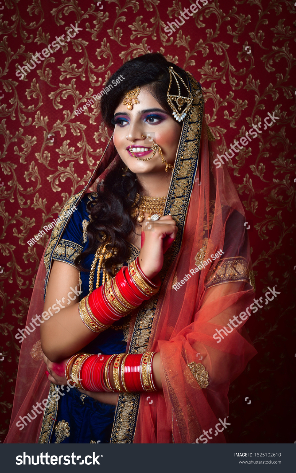 Portrait of an Indian Muslim bride wearing red sari with heavy jewelry in a banquet hall. Traditional Muslim Bride in wedding. #1825102610