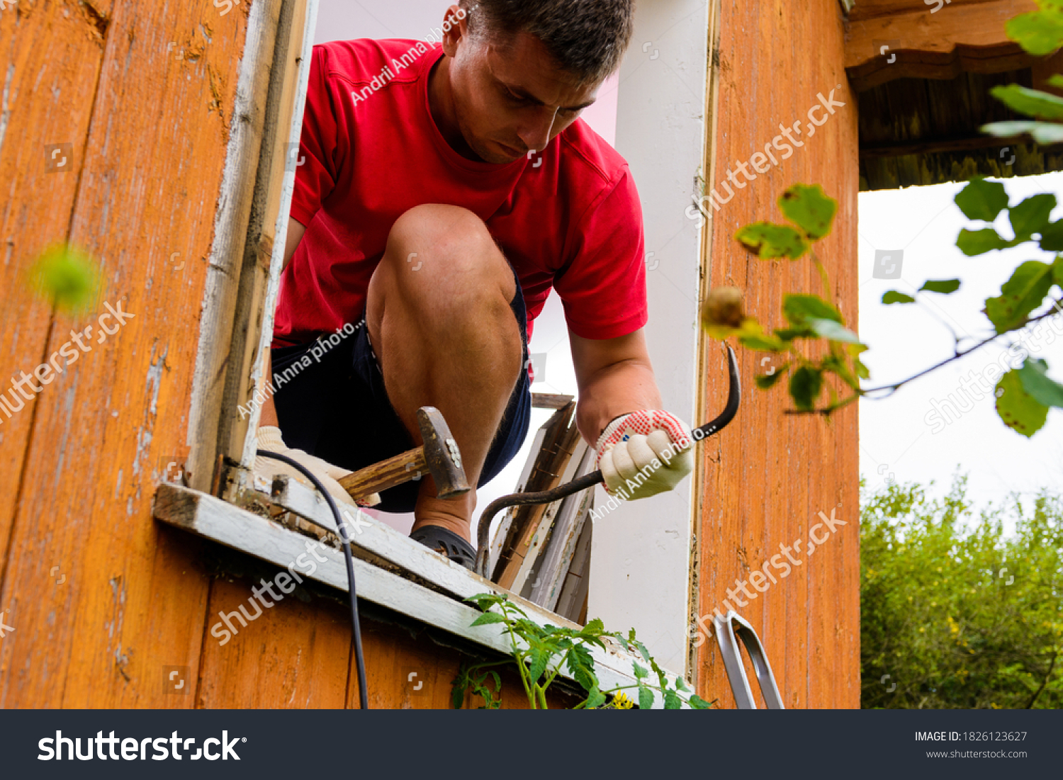 Replacement of a window and a window frame, dismantling of an old window in a private house in the countryside, the worker dismantles an old wooden window. #1826123627
