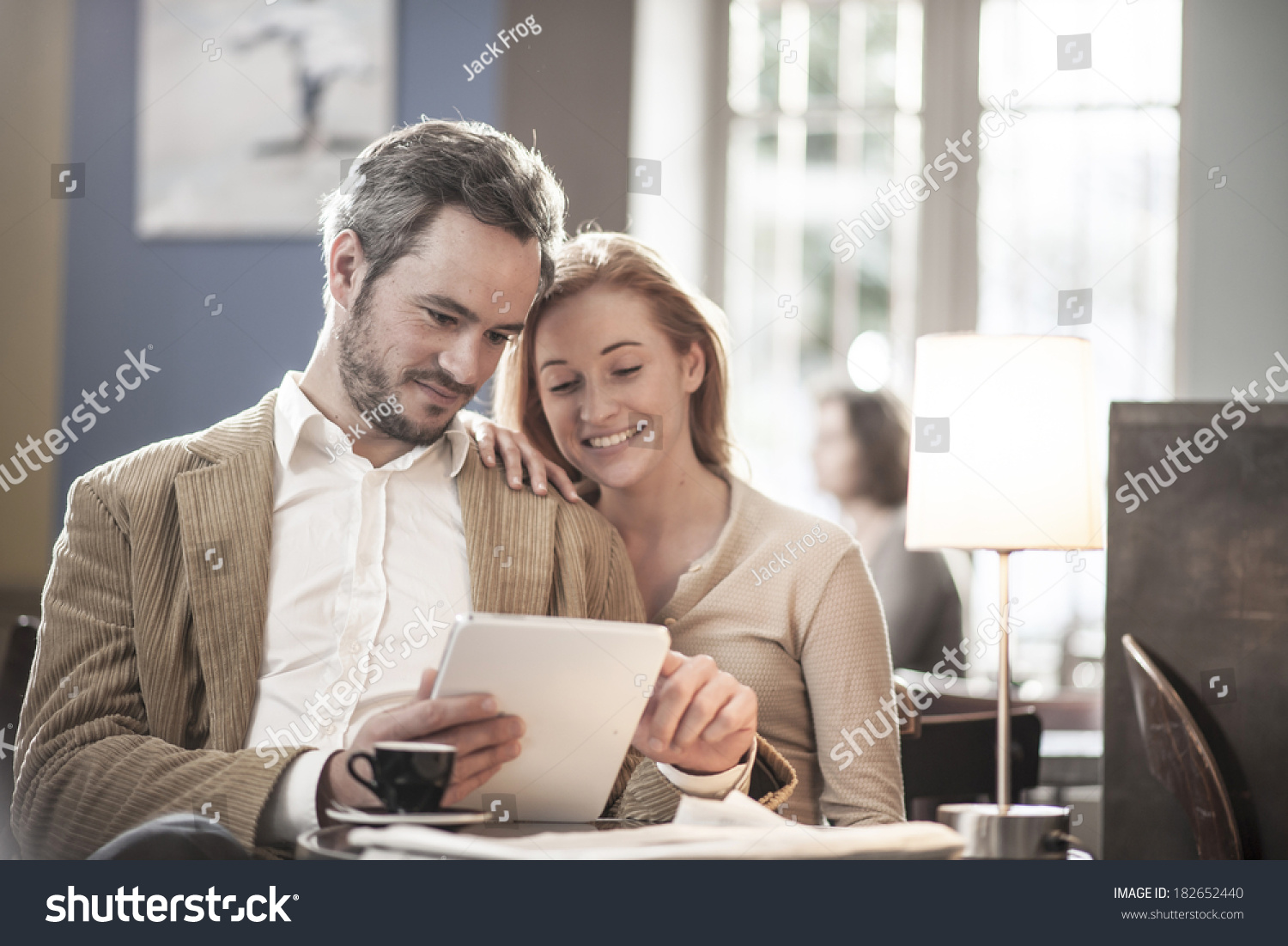 cheerful couple sitting in a cafe and using a digital tablet #182652440