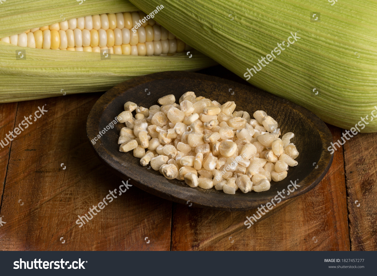 Zea mays - Wooden bowl with raw corn kernels, on wooden background. #1827457277
