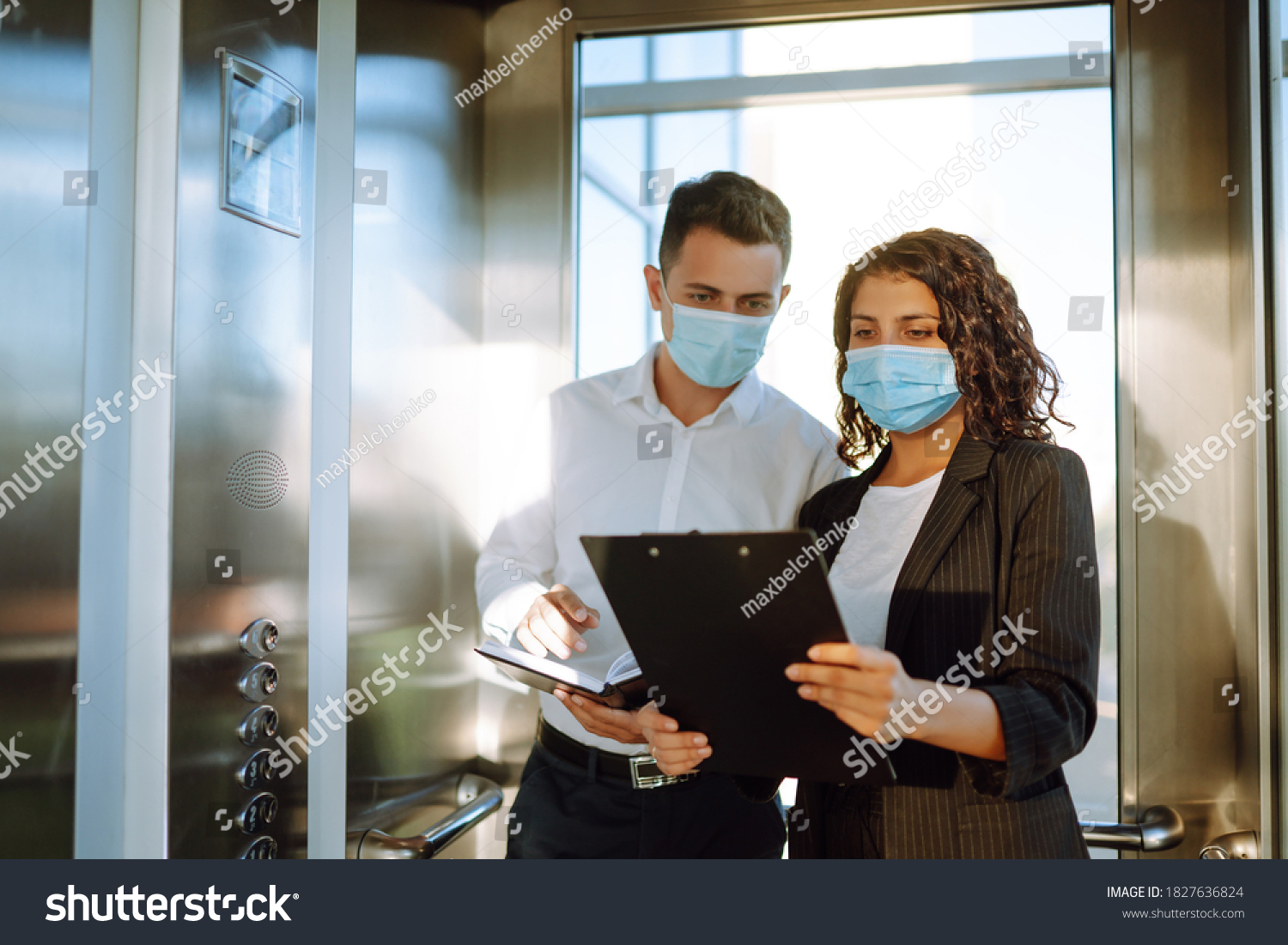 Business partners in protective sterile mask in the elevator. Colleagues talking while standing in elevator at  modern office. Teamwork during pandemic in quarantine city. Covid-19. #1827636824