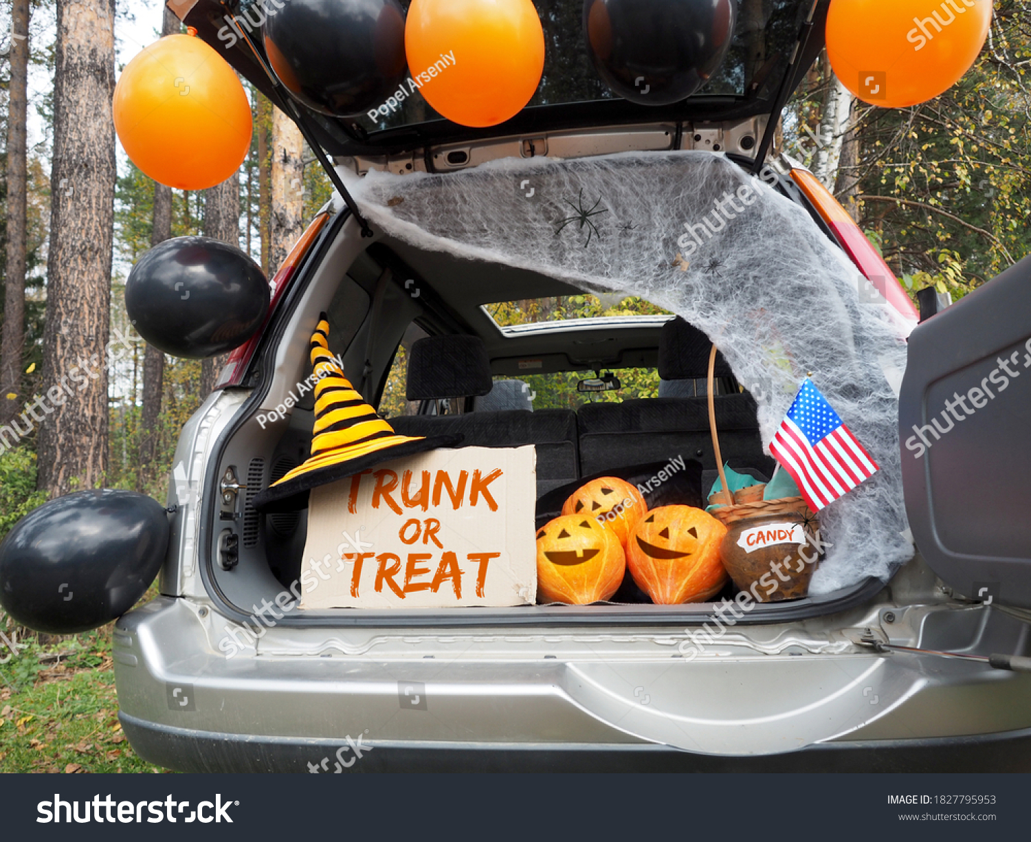 Trick or trunk. Concept celebrating Halloween in trunk of car. New trend celebrating traditional October holiday outdoor. Social distance and safe alternative celebration during coronavirus covid-19 #1827795953