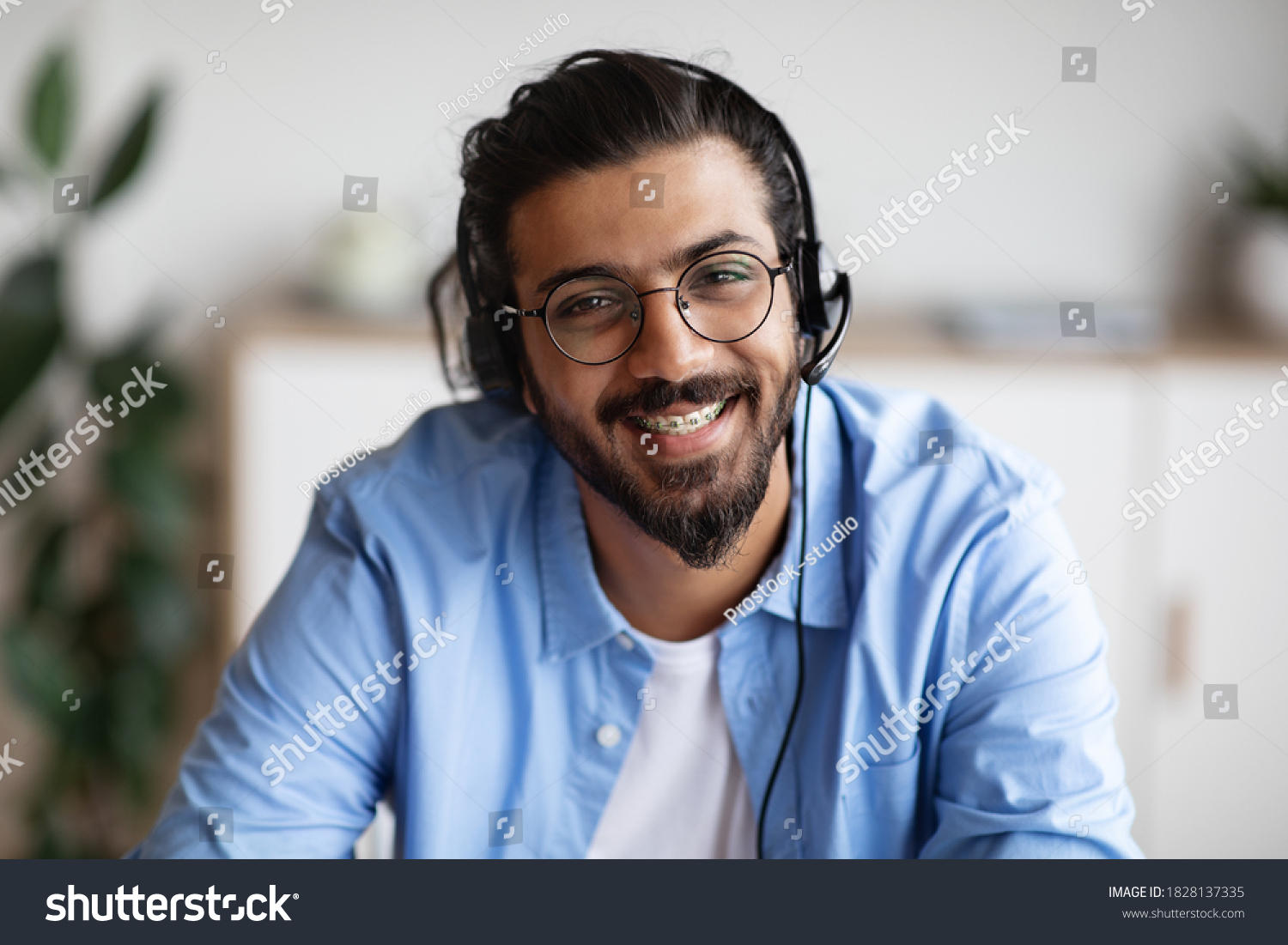 Call Center Operator. Closeup portrait of positive indian man customer service representative in headset, handsome western guy hotline manager looking at camera and smiling, selective focus #1828137335