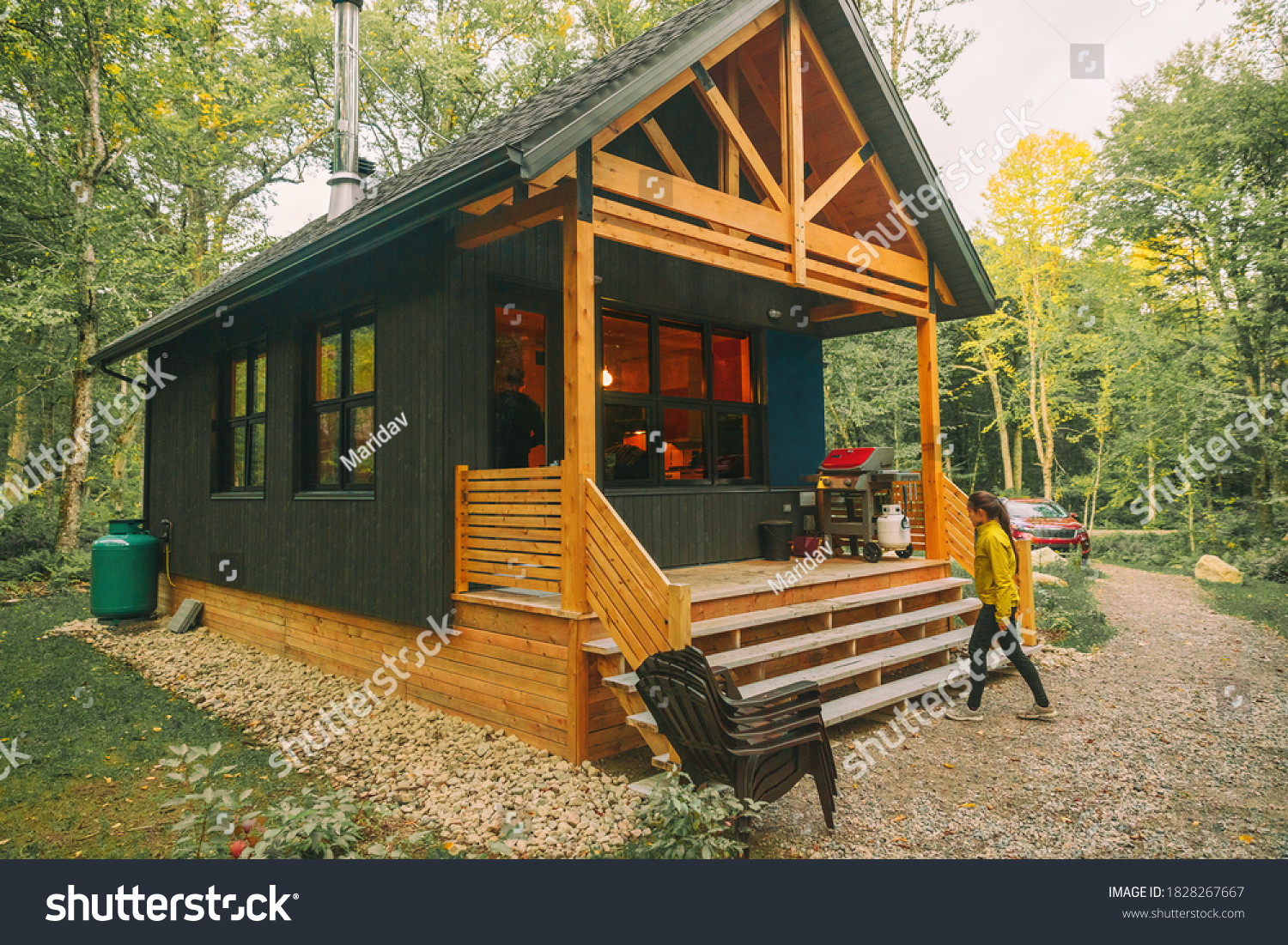 Vacation rental forest lodge countryside cabin by the lake for holidays in the wilderness. Woman entering her house home away from home. #1828267667