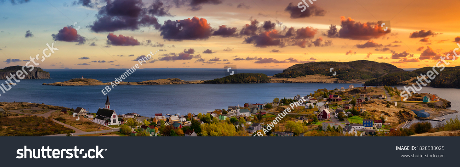 Aerial panoramic view of a small town on the Atlantic Ocean Coast. Dramatic Colorful Twilight Sky. Sunset or Sunrise. Taken in Trinity, Newfoundland and Labrador, Canada. #1828588025