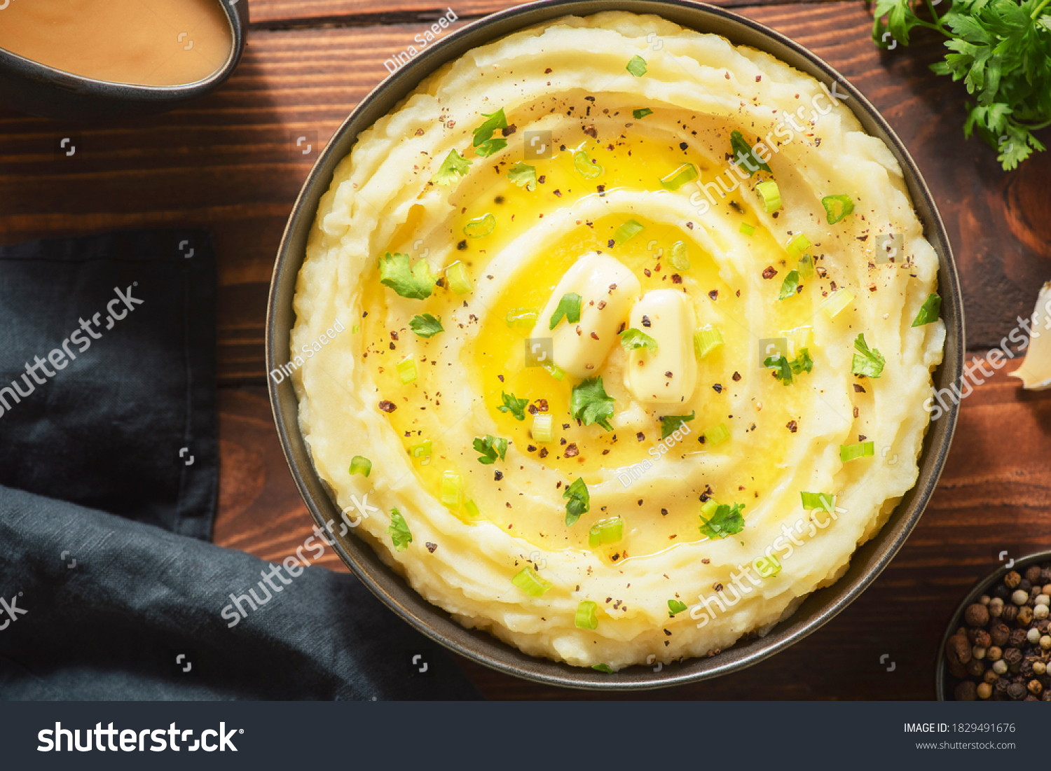 Delicious creamy mashed potatoes with butter, fresh herbs and freshly-cracked black pepper. Top view with close up. #1829491676