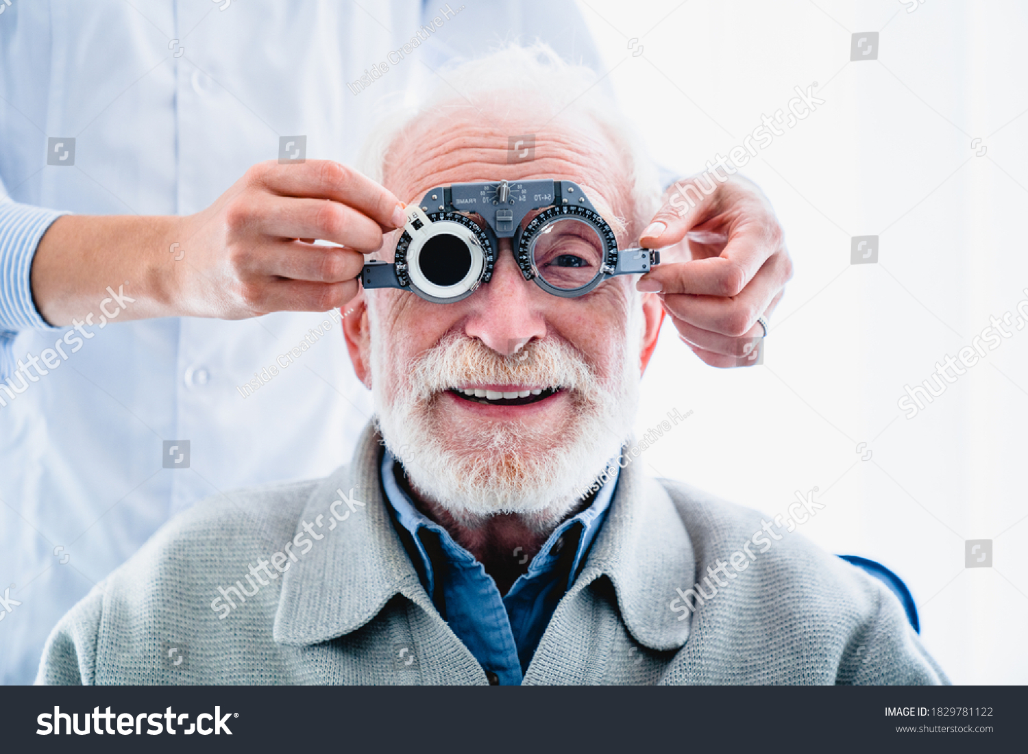 Oculist putting ophthalmic glasses on smiling elderly male patient #1829781122