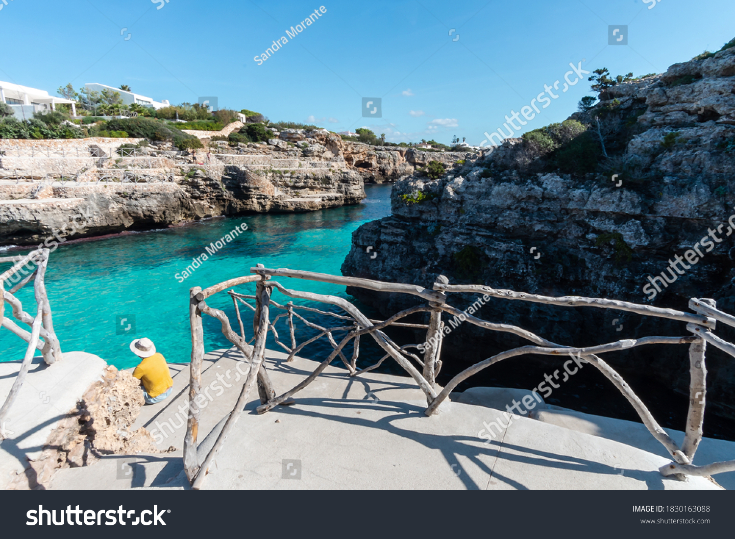 Turquoise waters of Cala en Brut, beach of Minorca, with a man with hat contemplating the view, Balearic Islands in Spain #1830163088