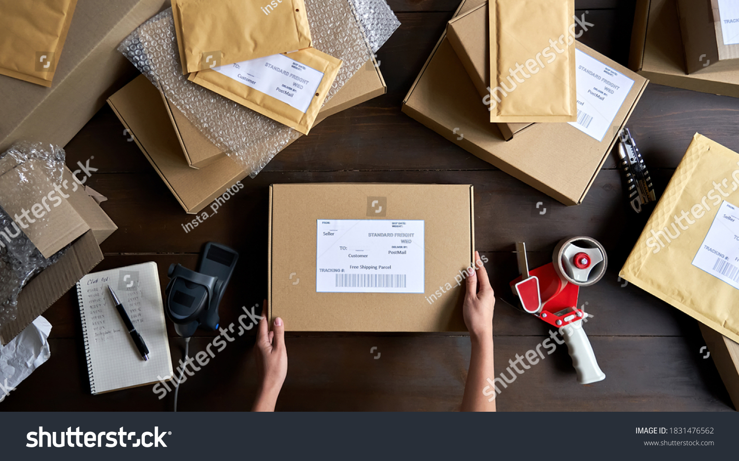 Above table top view of female warehouse worker or seller packing ecommerce shipping order box for dispatching, preparing post courier delivery package, dropshipping shipment service concept. #1831476562