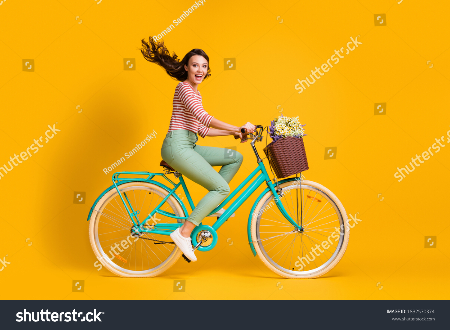 Full length body size side profile photo of cheerful girl riding blue bicycle with basket of flowers isolated on vibrant yellow color background #1832570374