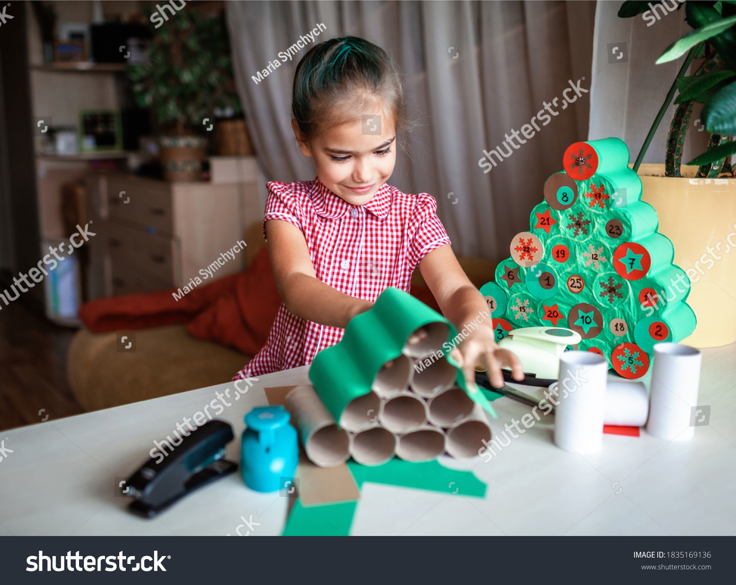 Cute little kids making handmade advent calendar with toilet paper rolls at home. Glue, colored paper, cut punch to hide sweets and candies in rolls. Seasonal activity for kids, zero waste holidays #1835169136