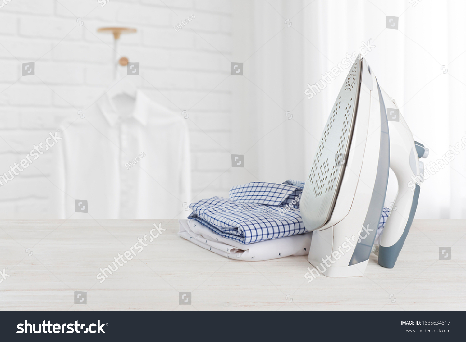 Iron on wooden board with clothes, ironing board household concept #1835634817