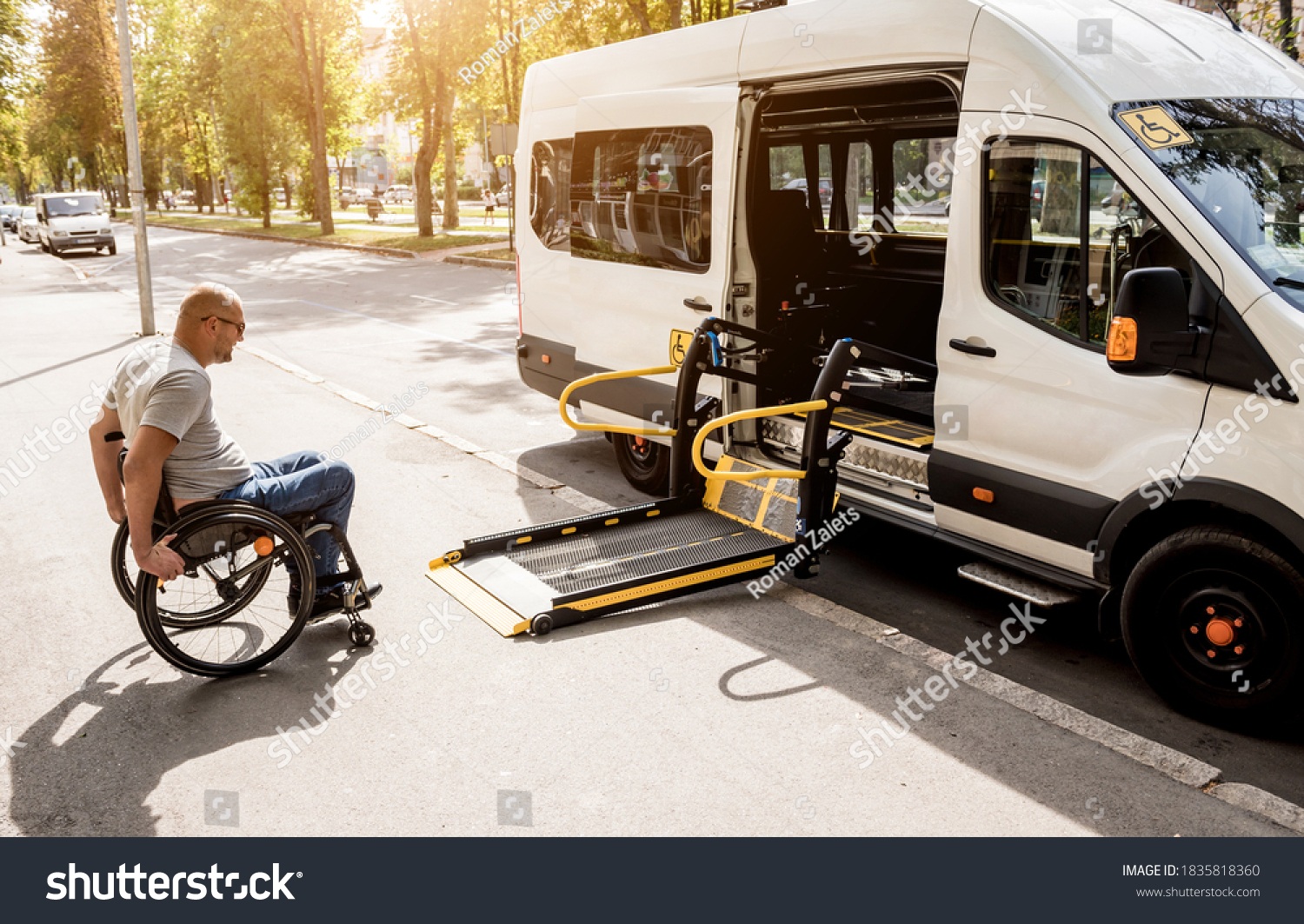 A man in a wheelchair moves to the lift of a specialized vehicle  #1835818360