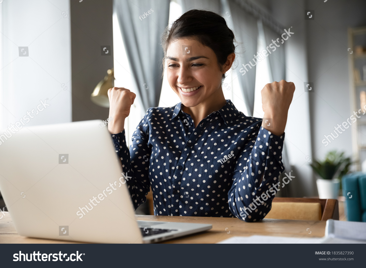 Overjoyed indian ethnicity girl sit at desk looks at laptop screen read incredible news clench fists makes yes gesture celebrate on-line lottery gambling win, getting new job offer feels happy concept #1835827390