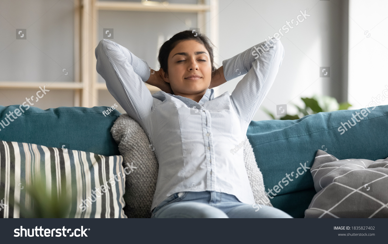 Serene Indian woman closed eyes breath fresh humified air in cozy living room alone put hands behind head lean on sofa having day nap alone, reduces fatigue, enjoy pleasant thoughts, no stress concept #1835827402