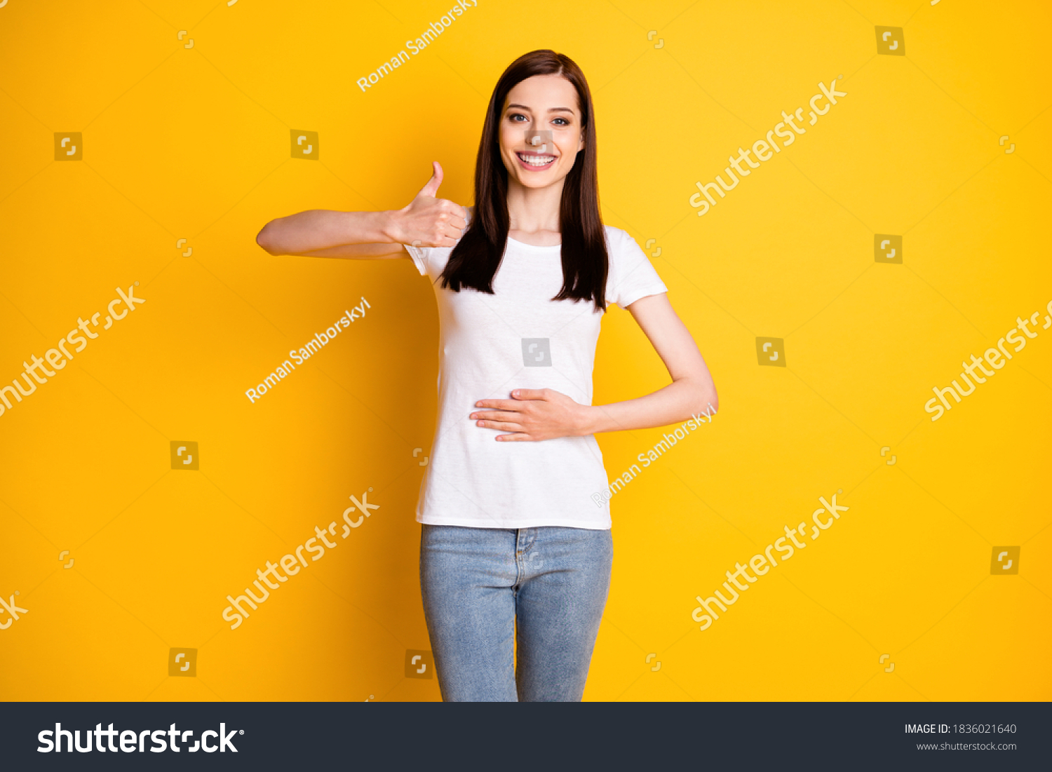 Portrait of positive cheerful girl touch hand abdomen enjoy healthy, digestive nutrition show thumb up sign wear white denim isolated over shine color background #1836021640