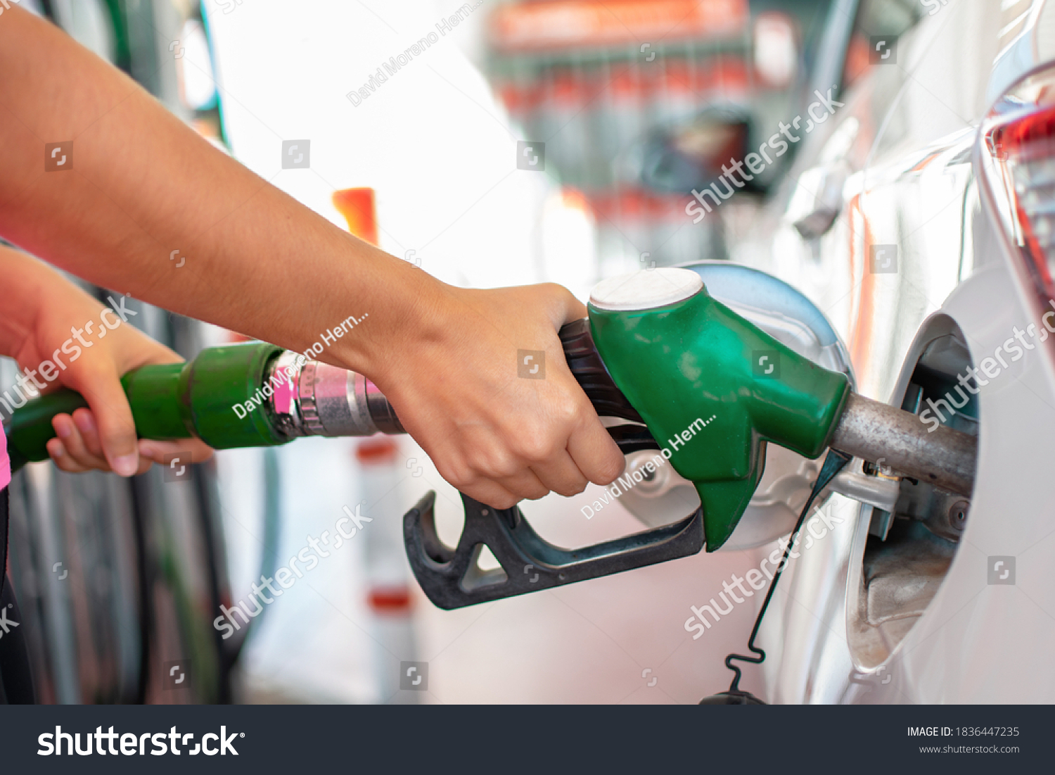 Filling up the car with petrol. Woman's hands pouring gasoline or gas into her car tank at fuel station #1836447235