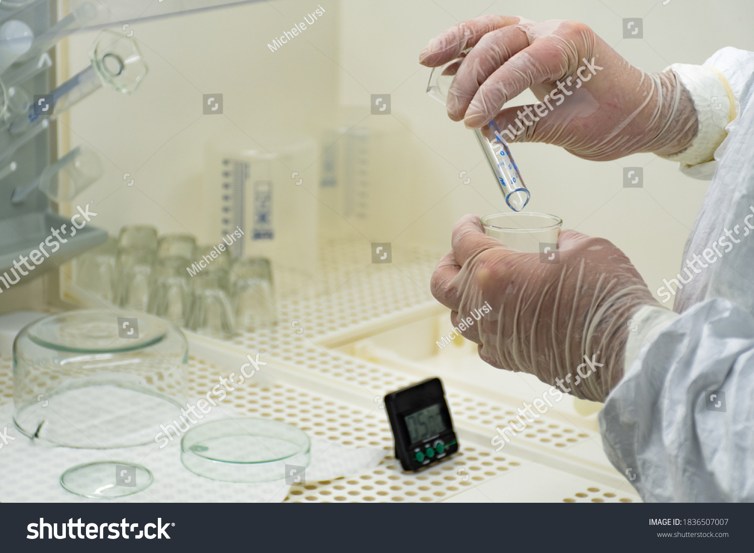 Scientist in protective white coat, mask and gloves analyzes a virus or bacteria sample in a laboratory with vials, glass flasks and chemicals. Medical lab test, new vaccine research or development #1836507007