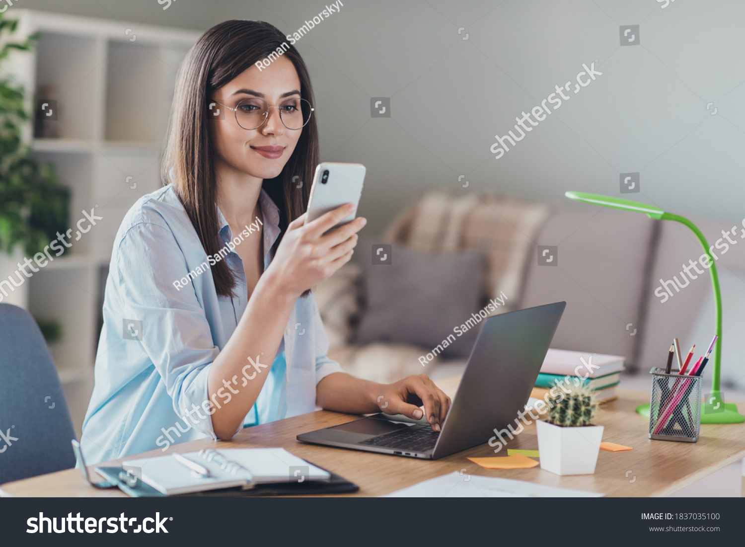 Photo of adorable young lady hold telephone look screen palm keyboard wear glasses shirt in home office indoors #1837035100