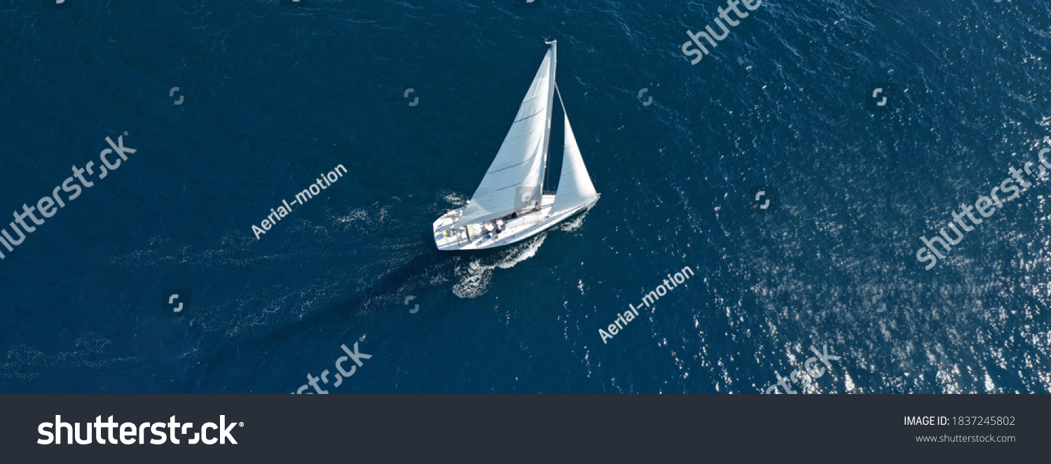 Aerial drone ultra wide photo of beautiful sailboat cruising deep blue open ocean Mediterranean sea #1837245802