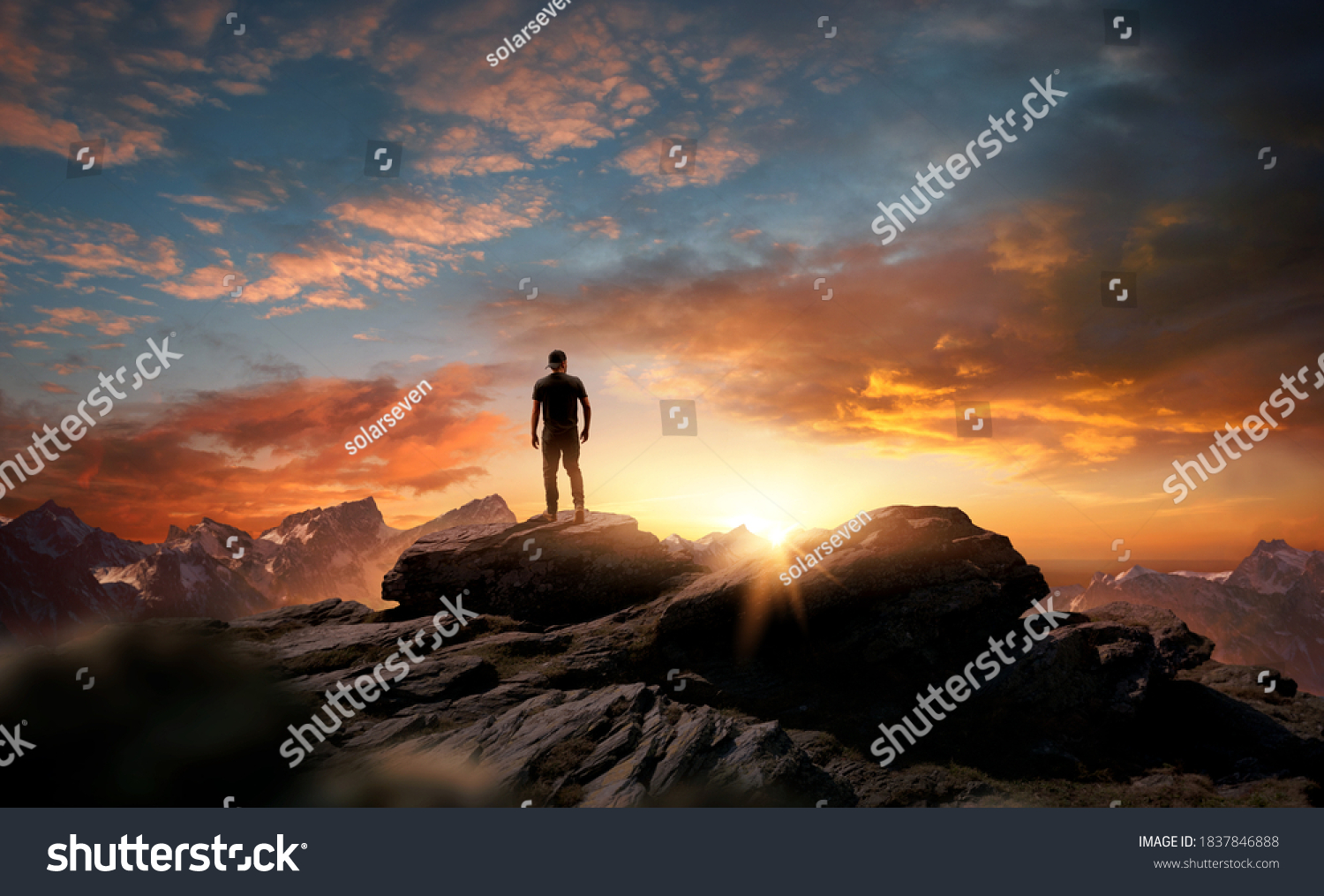 A man standing at the top of a mountain as the sun begins to set. Goals, hopes and aspirations concept. Photo compostion. #1837846888