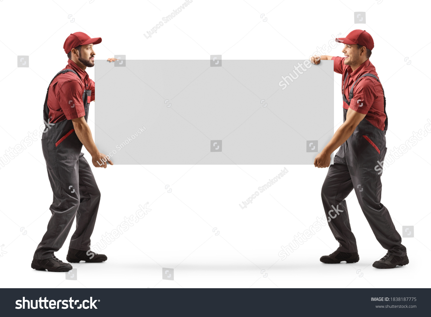 Full length shot of two male workers carrying a blank panel board isolated on white background #1838187775