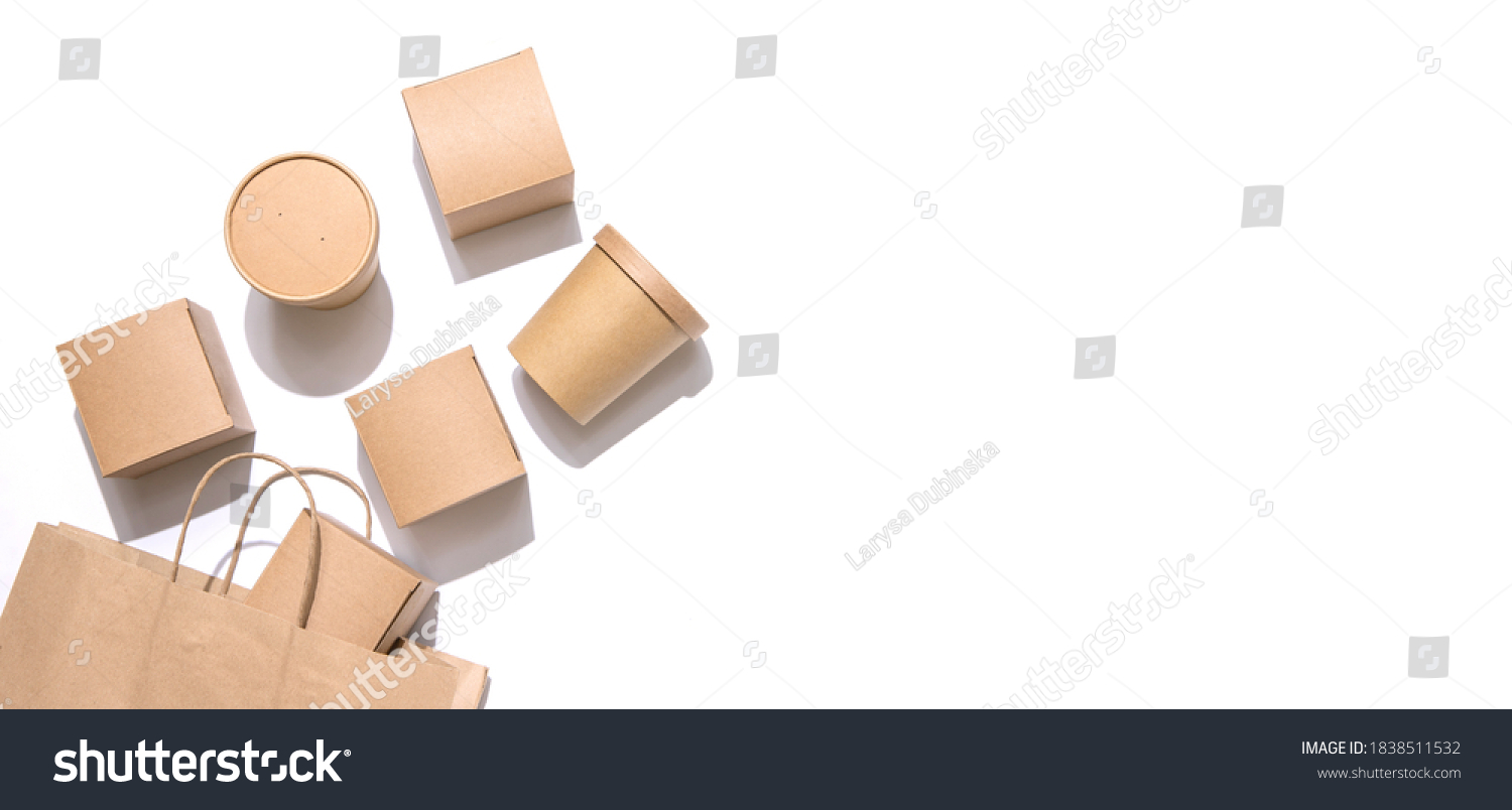 Cardboard containers for food, drinks and items drop out of the craft bag.  Isolated on white background, top view. Copy space. Delivery, takeaway food, eco-friendly packaging concept. Nobody. #1838511532