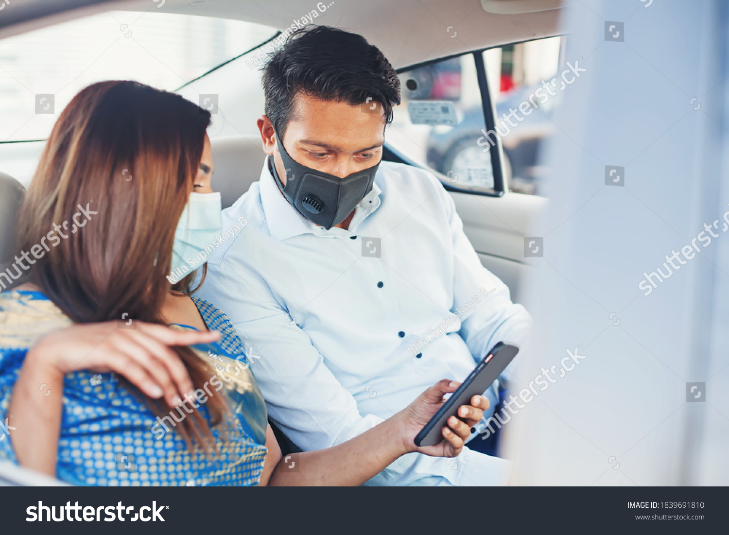 Indian couple wearing face medical masks taking a cab and using mobile phone app for booking #1839691810