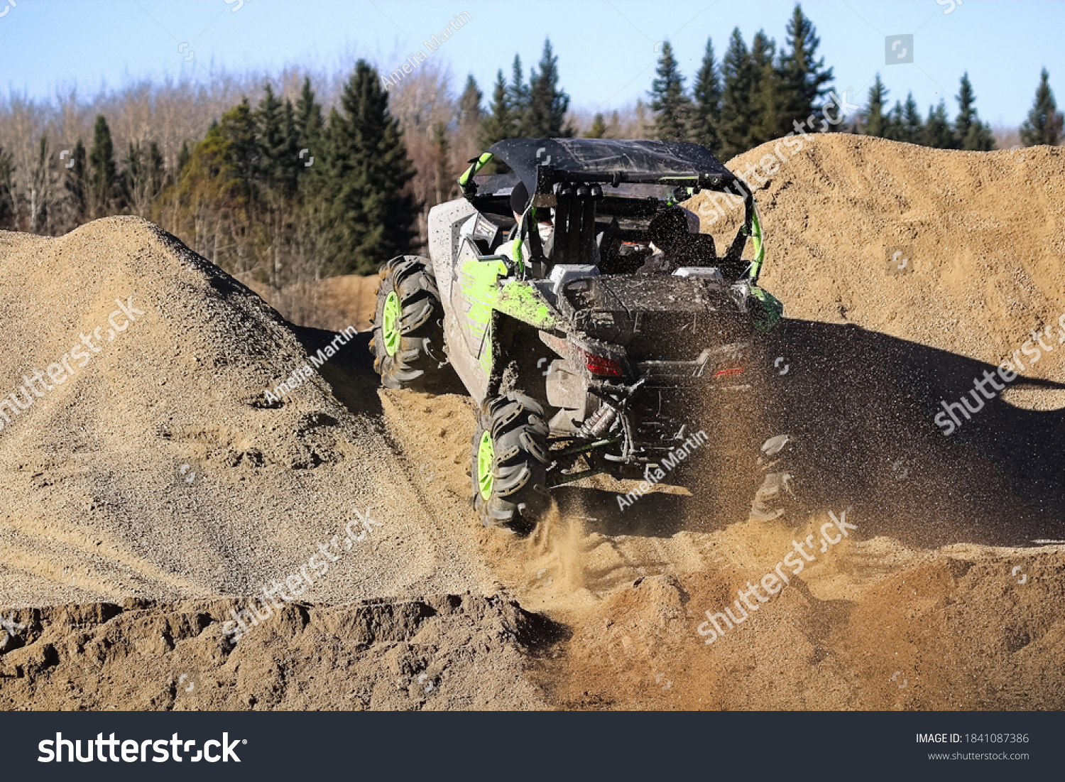 A side-by-side ripping up dirt as it goes up a gravel hill #1841087386