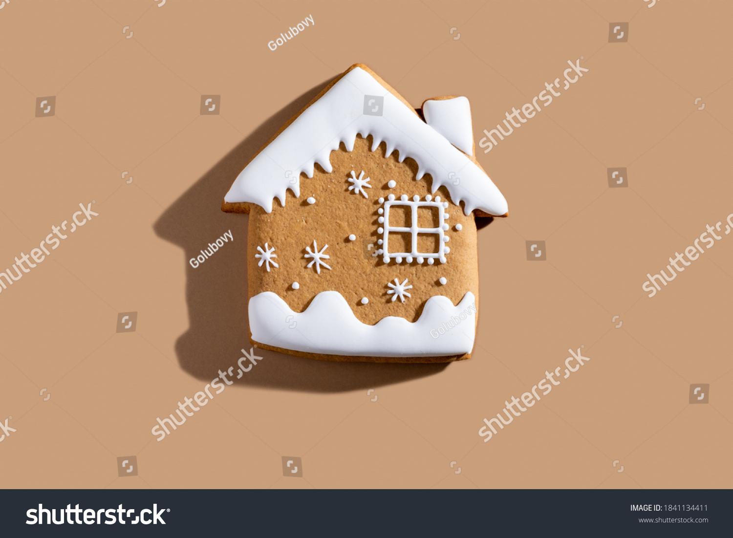 Christmas bakery. Festive traditional cookies. Homemade culinary. Gingerbread biscuit figure house with white icing ornament isolated on beige pastel background. #1841134411
