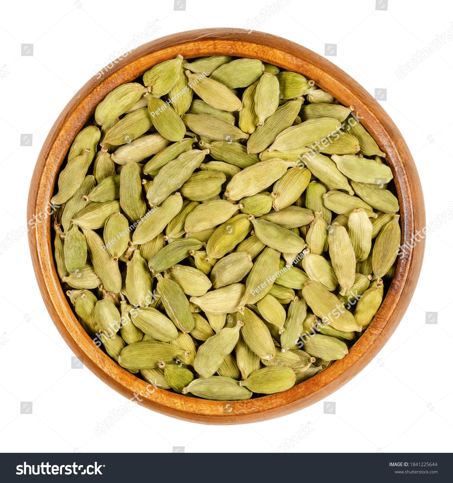 Green cardamom pods in a wooden bowl. True cardamom, processed pods and seeds of Elettaria cardamomum, sometimes cardamon or cardamum, used as a spice. Close-up, from above, isolated macro food photo. #1841225644