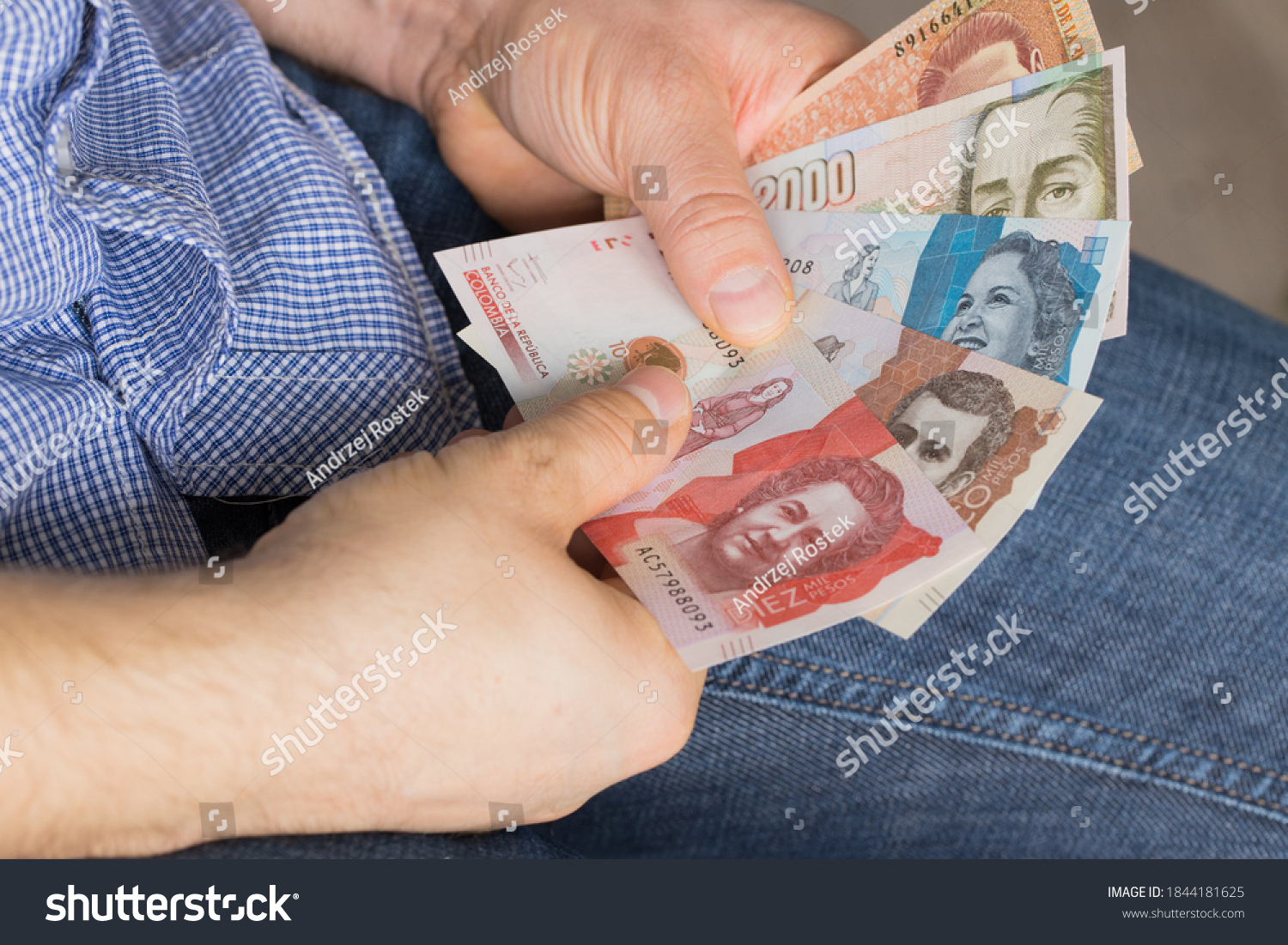 a man holding a bundle of money in his hands, various Colombian pesos #1844181625