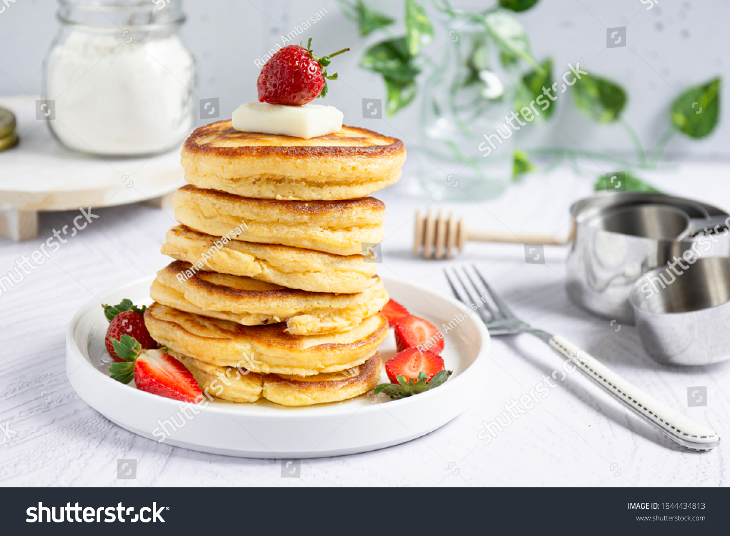 Close up view of a stack of pancakes with butter, strawberry and honey, bright mood, selective focus #1844434813