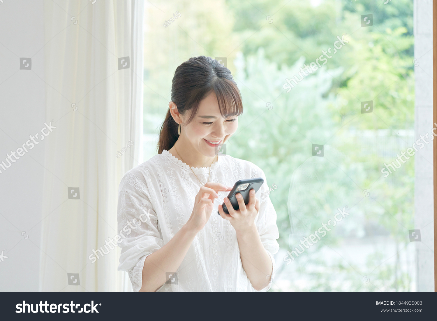 Asian woman using the smart phone at the living room #1844935003