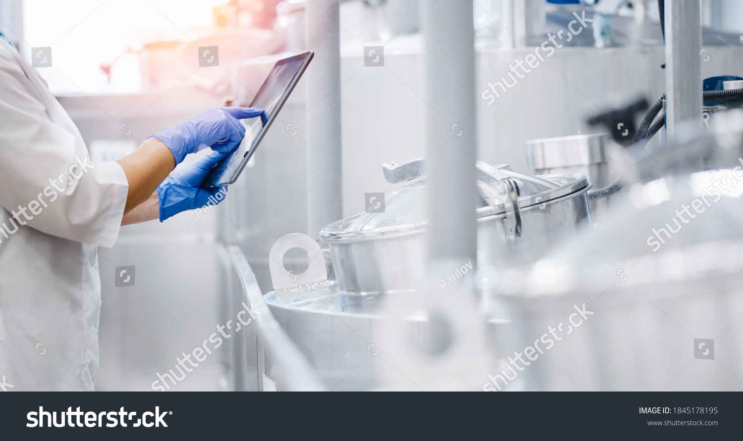 Concept food industry banner. Factory worker inspecting production line tanker in of dairy factory with computer tablet. #1845178195