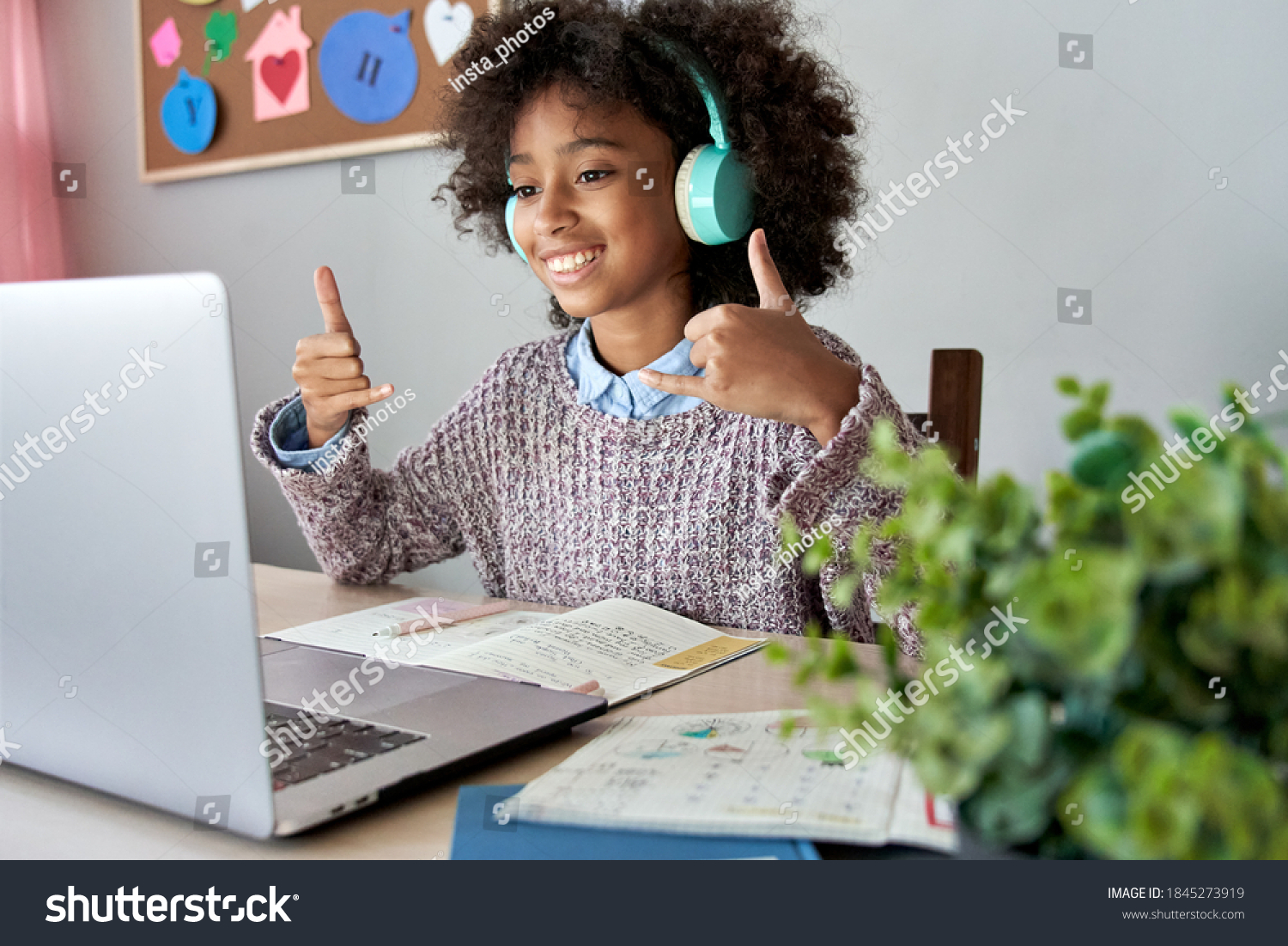 Smiling african mute child school girl learning online class on laptop communicating with teacher by video conference call using sign language showing play hand gesture on virtual therapy lesson. #1845273919
