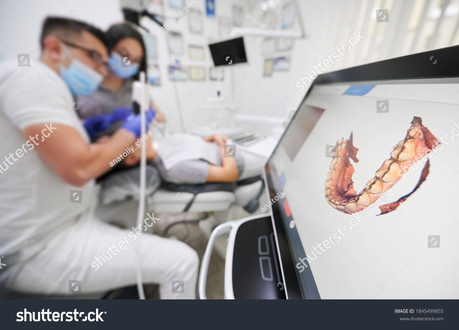 Dentist scanning patient's teeth with modern scanning machine. Digital print of patient's teeth is on big screen. Modern high precision technologies. Concept of modern dentistry #1845499855