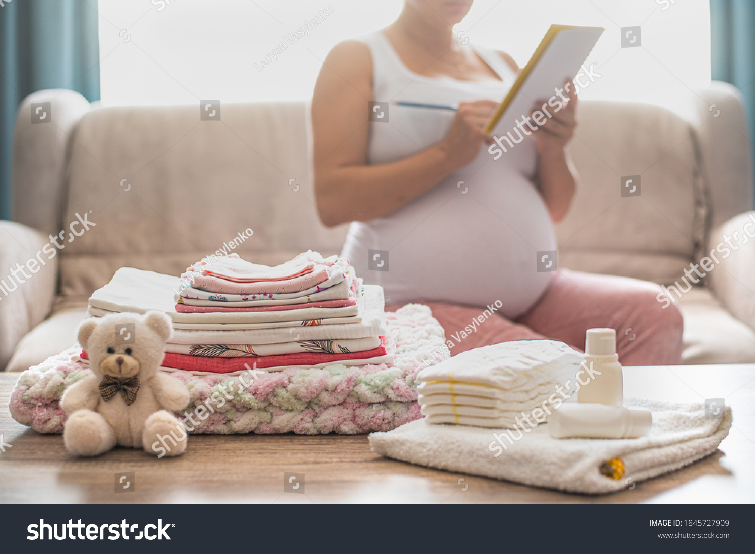 Pregnant woman is getting ready for the maternity hospital, packing baby stuff. pregnant woman preparing and planning baby clothes.  List of things in the hospital.   #1845727909