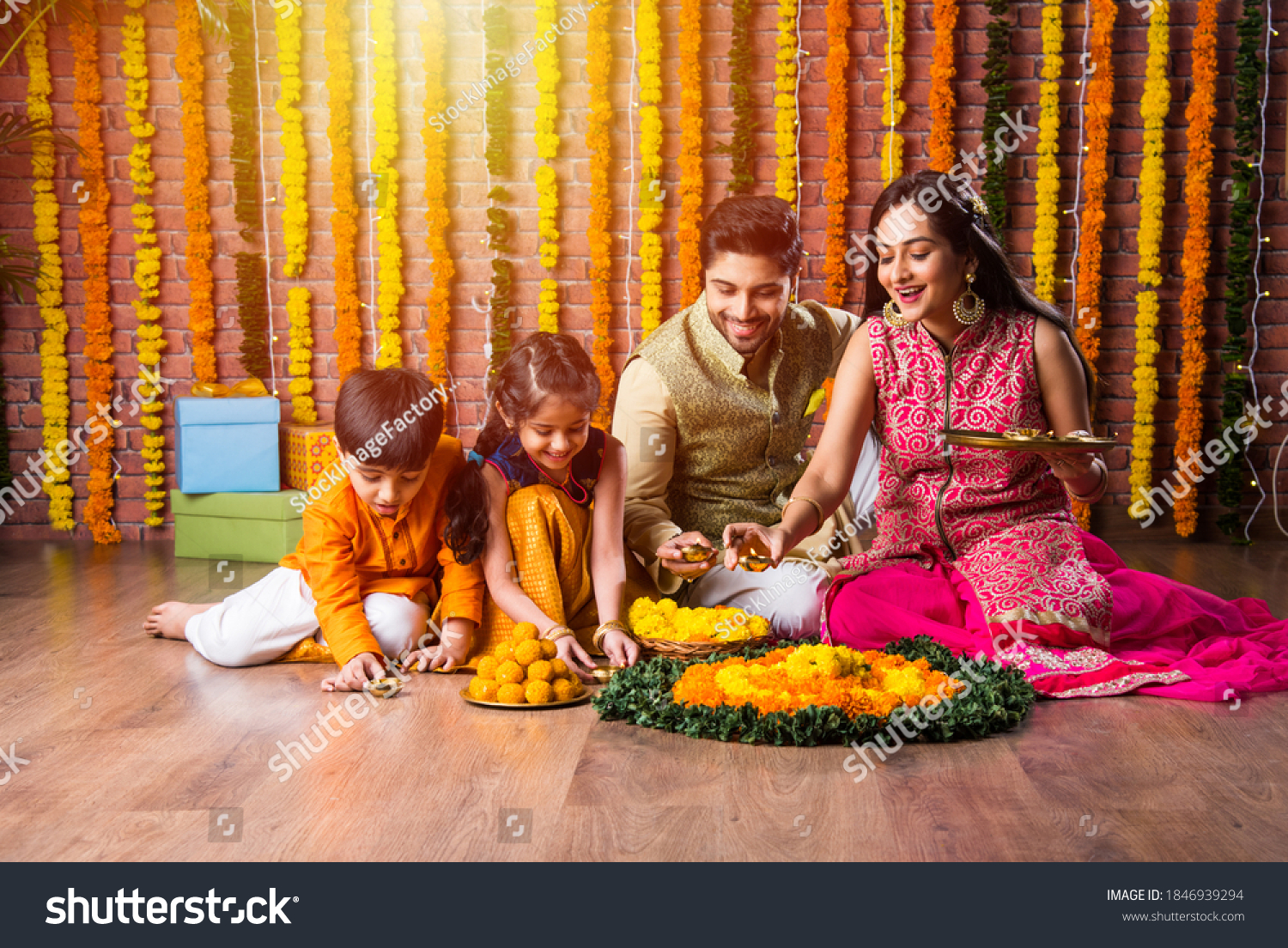 Indian family lighting or arranging oil lamp or diya around flower rangoli on diwali festival night #1846939294