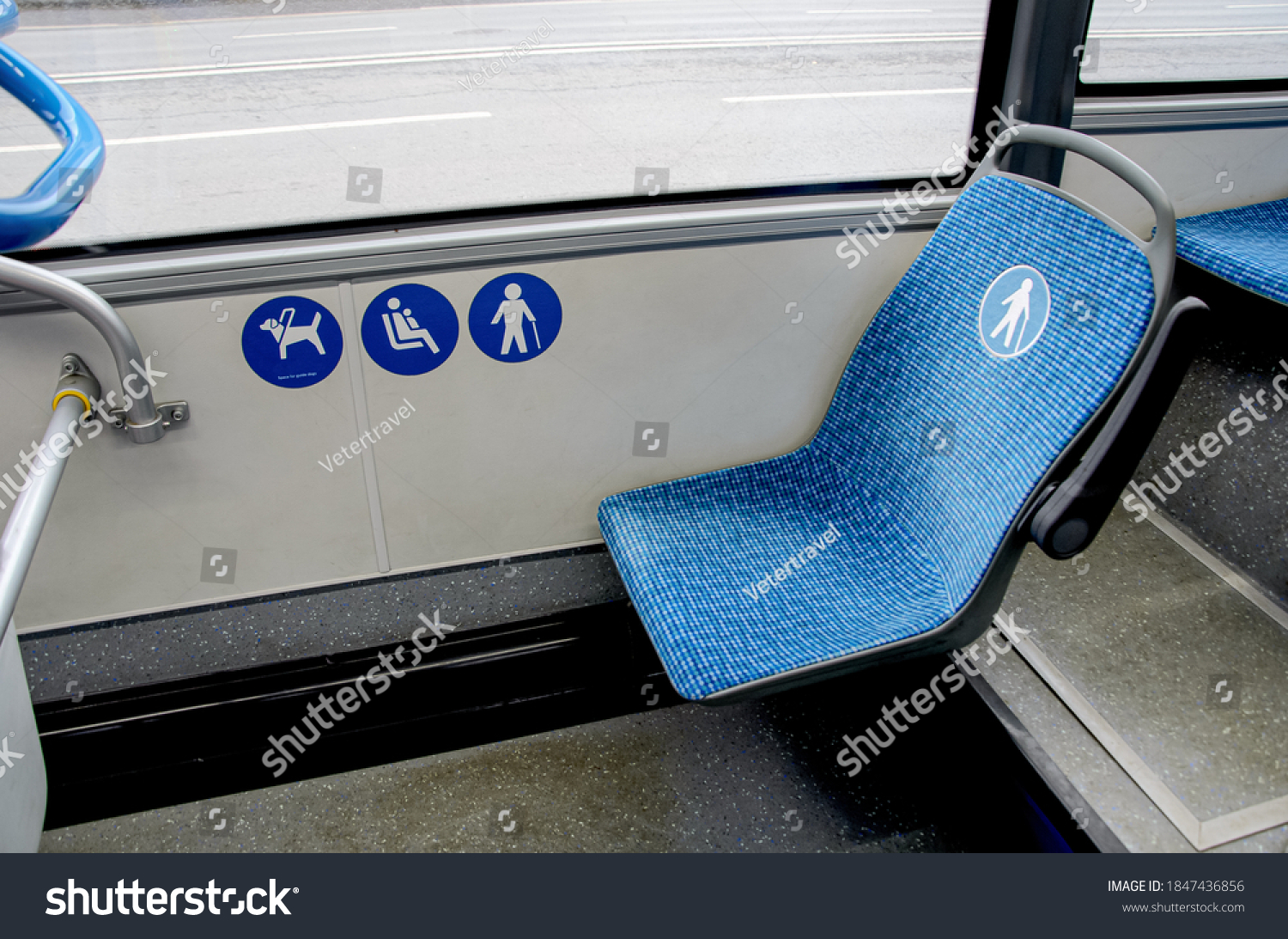 Blue fabric seat in the bus for elderly, people with disabilities and passengers with children. Space for guide dog in bus. Special seats in public transport for certain categories of passengers. #1847436856