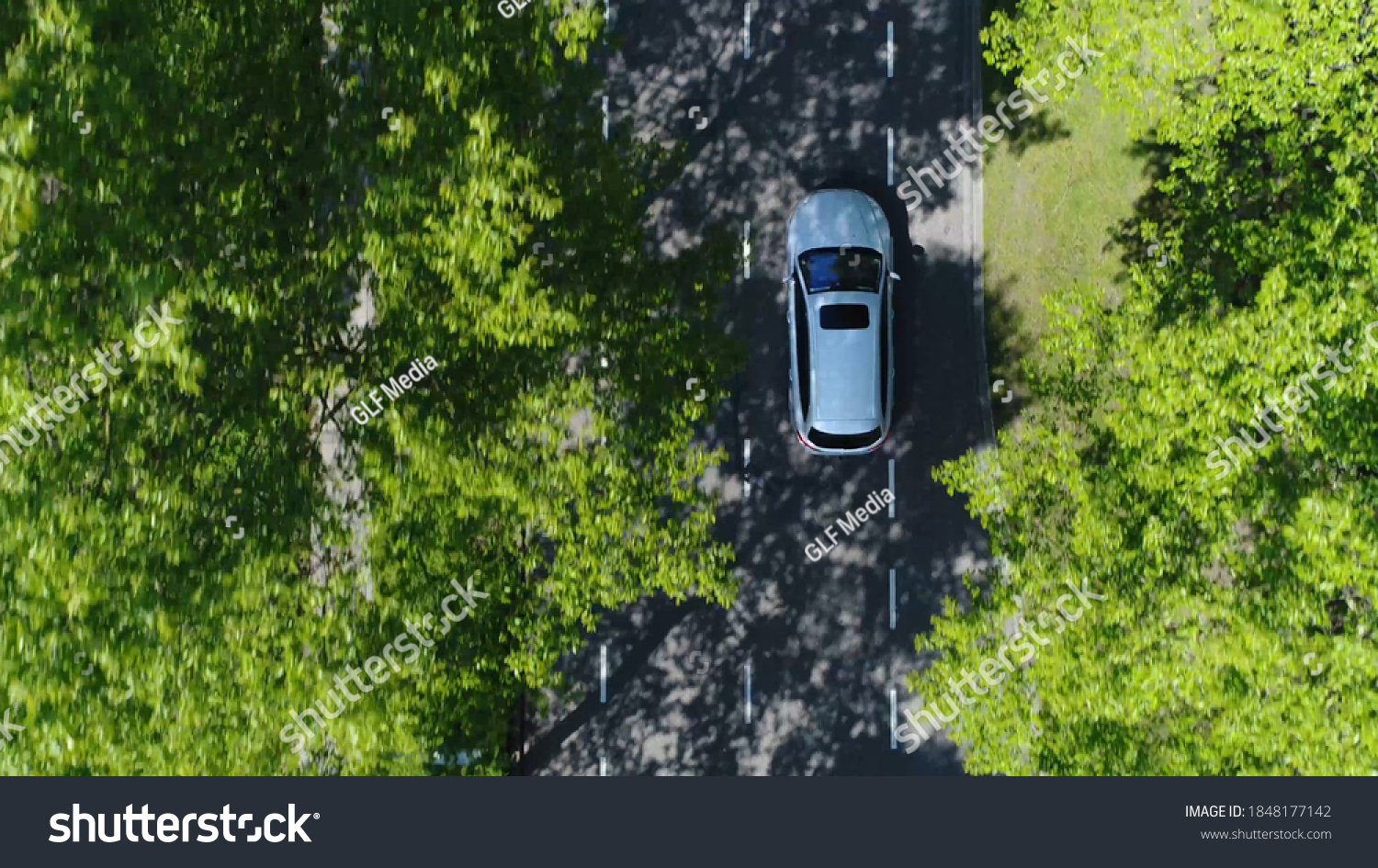 Aerial top down view of grey station wagon vehicle overtaking drone camera driving over straight road testing area for development of self driving electronic automobiles ev's 4k high resolution #1848177142
