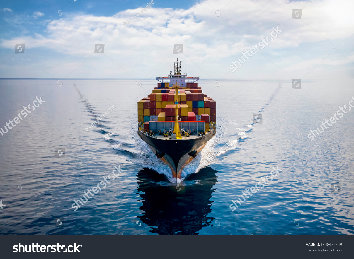Aerial front view of a loaded container cargo vessel traveling over calm ocean #1848489349