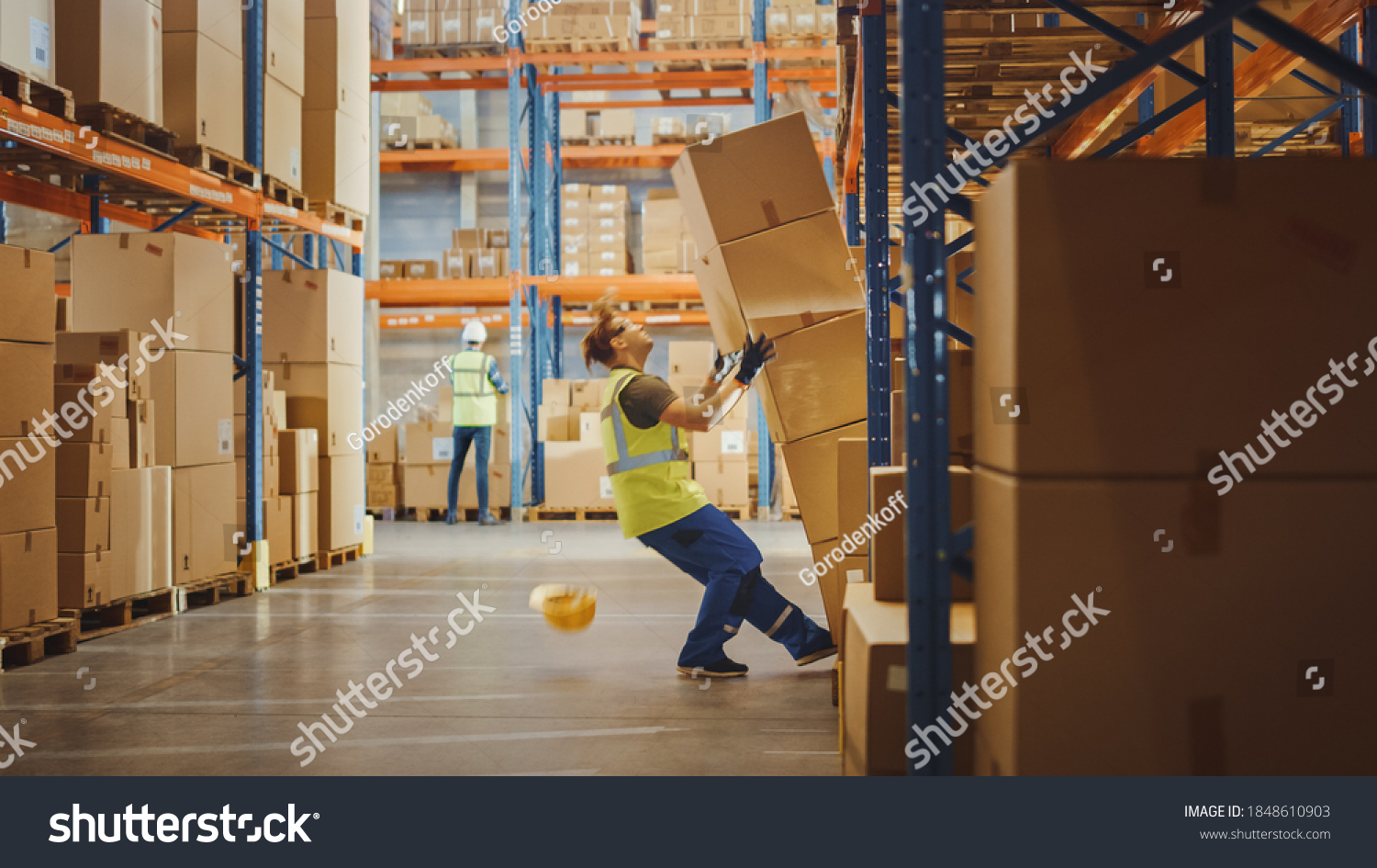 Shot of a Warehouse Worker Has Work Related Accident. He is Falling Down BeforeTrying to Pick Up Heavy Cardboard Box from the Shelf. Hard Injury at Work. #1848610903