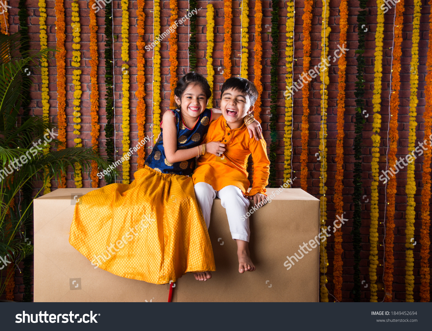 Indian kids, little brother and sister celebrating Diwali, Raksha Bandhan, Bhai Dooj with big gift box and sweet laddoo #1849452694