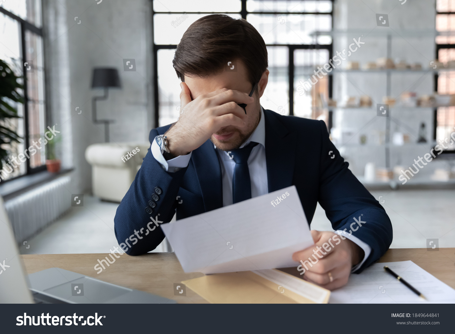 Frustrated 30s employee in formal wear holding paper dismissal notice, unhappy confused young businessman feeling stressed about bad news in letter, company bankruptcy or financial problems. #1849644841