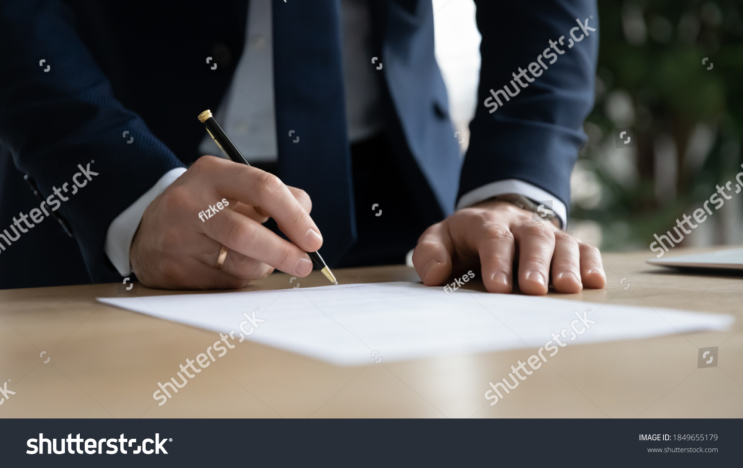 Close up young businessman standing near table with pen in hands, ready signing profitable offer agreement after checking contract terms of conditions, executive manager involved in legal paperwork. #1849655179