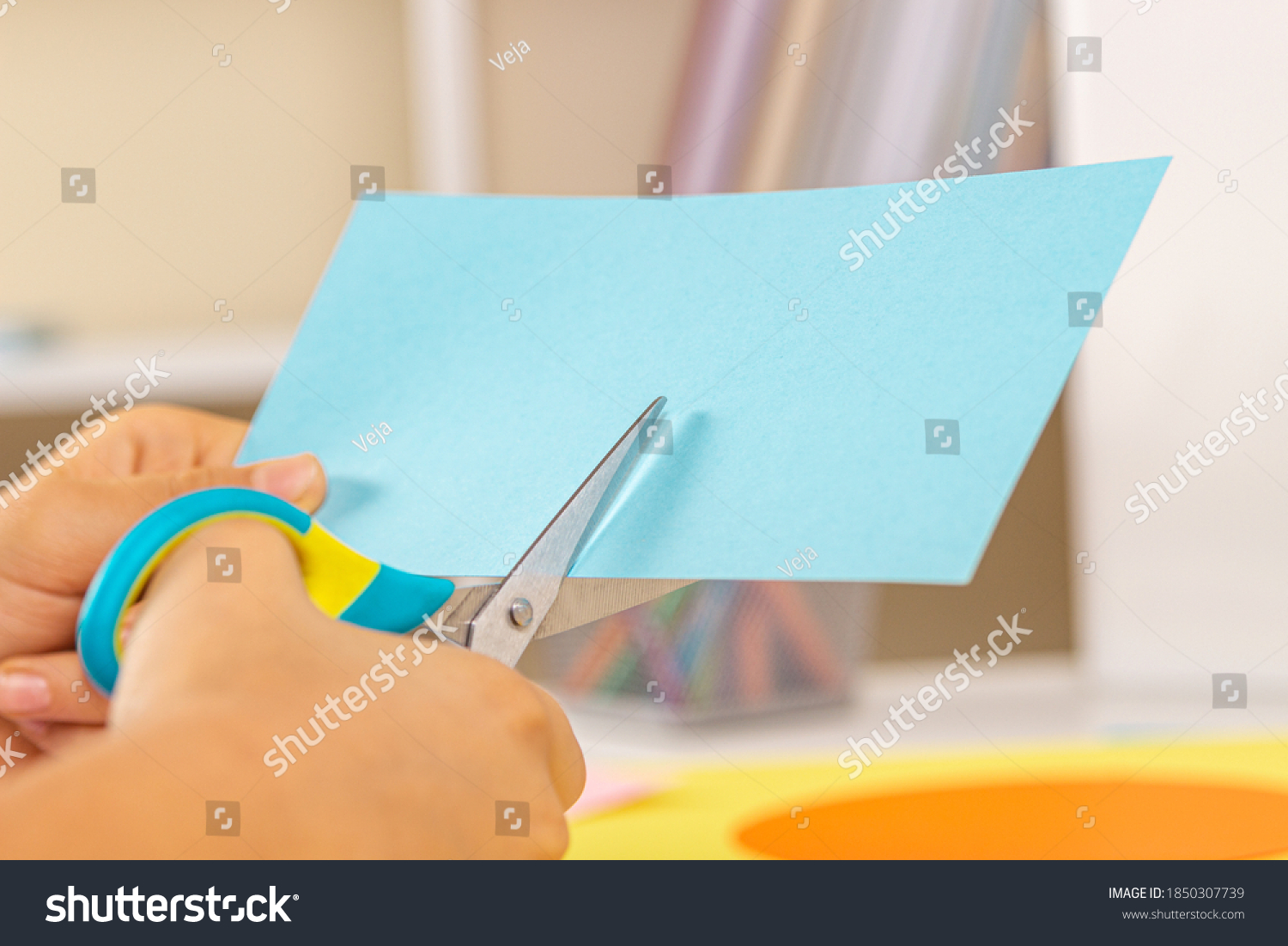 Kid hands cutting light blue colored paper with scissors. Education, learning, paper craft, entertainment #1850307739