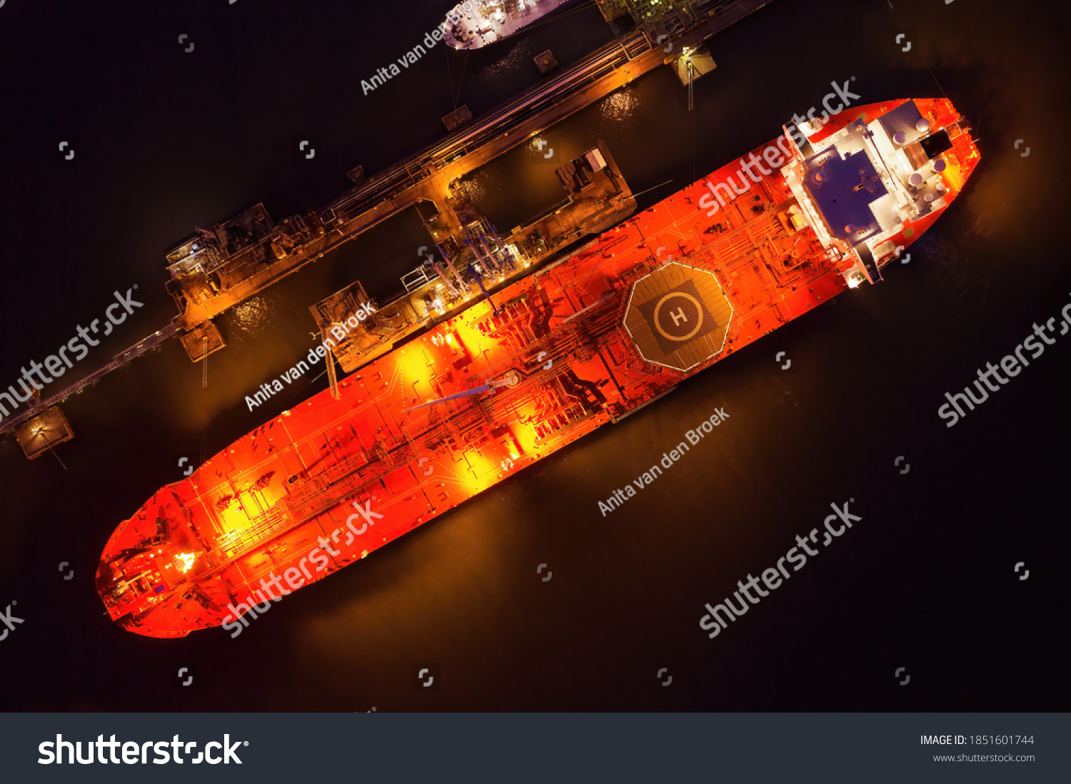 Crude oil shuttle tanker docked at night wtih light on creating an atmospheric glow with space for text. #1851601744