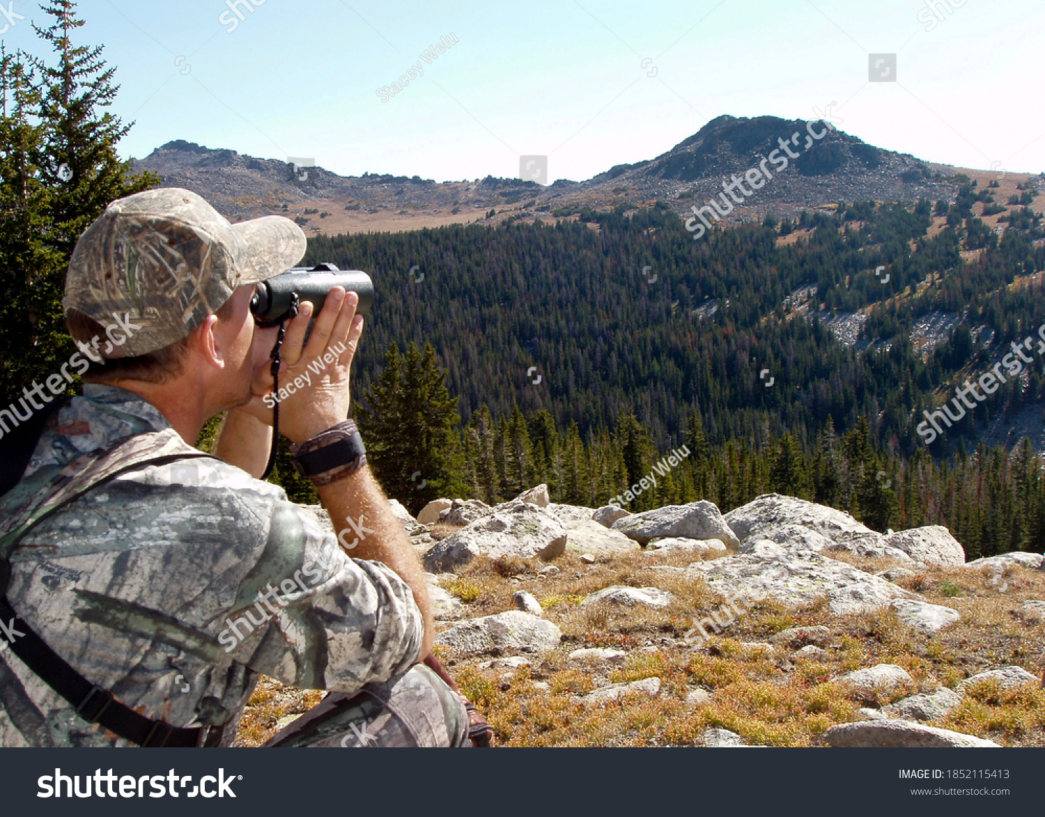 Hunter in camouflage using binoculars to search Montana hills for animals #1852115413
