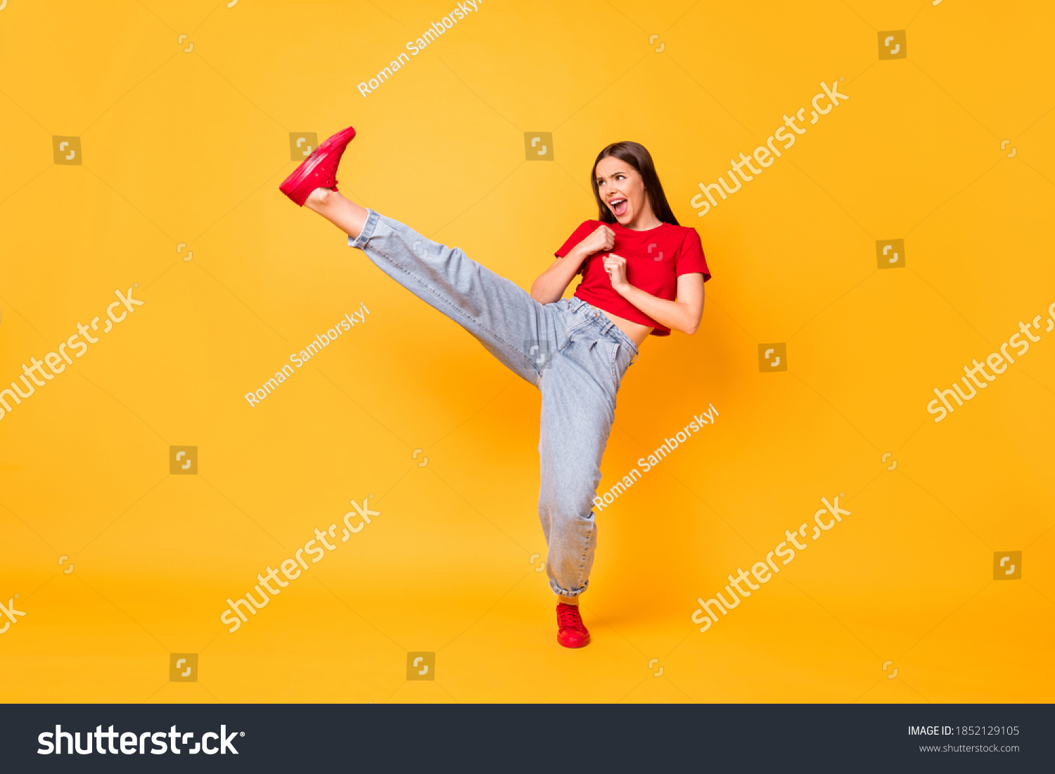 Full length photo focused girl practicing kicks raise leg exercise wear red crop top jeans isolated yellow color background #1852129105